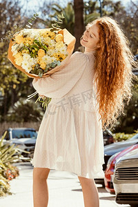 人背面摄影照片_背面视图微笑的妇女户外与花束春天的花