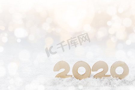 木号2020年在雪中，在闪光的bokeh背景的新年快乐的概念’ 2020年雪中的木制品