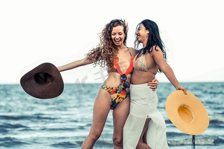 快乐的女人穿着比基尼跳舞在热带沙滩在暑假。旅行生活方式快乐的女人在夏天的沙滩上跳舞。