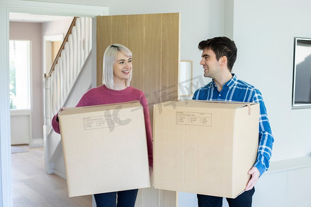 年轻夫妇在搬家日携带箱子进入新家
