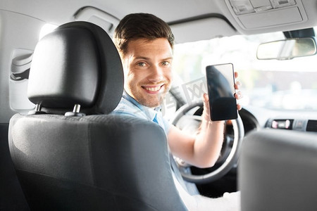 智能驾驶摄影照片_运输，驾驶和技术概念—人或汽车司机显示智能手机。男子或汽车司机显示智能手机