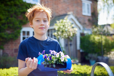 男孩的肖像拿着自制的密封的植物持有者从塑料瓶包装废物在花园在家里