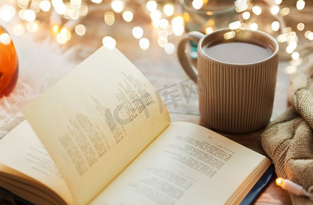 概摄影照片_Hygge和舒适的家庭概念书和一杯咖啡或热巧克力在桌子上。桌上有一本书和一杯咖啡或热巧克力