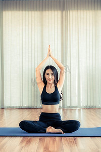 年轻女子练习瑜伽的位置在室内健身房工作室。健康和健康的生活方式理念。