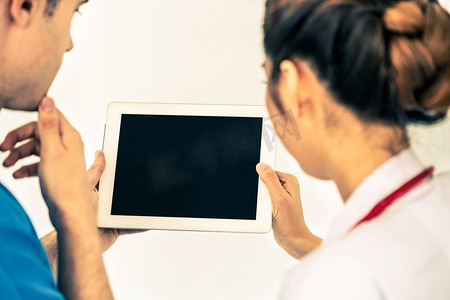 名医简介摄影照片_女医生在与医院的另一名医生讨论时使用平板电脑。医疗保健人员和医生服务。