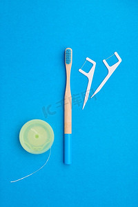 蓝色口腔健康摄影照片_牙刷和口腔护理工具放在蓝色背景上方，俯视复印空间平放。牙齿护理、牙齿卫生和健康理念。