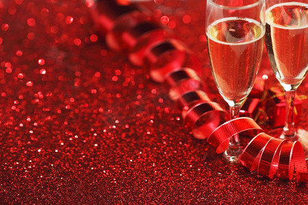 闪光框摄影照片_玻璃与香槟和礼物在红色闪光背景