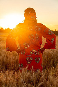 女人臀部摄影照片_传统衣服的非洲妇女站在她的臀部她的手在大麦或小麦作物领域在日落或日出