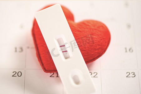 全年日历摄影照片_怀孕测试孕妇概念/阳性结果日历背景上两行计划生育和保健和红心