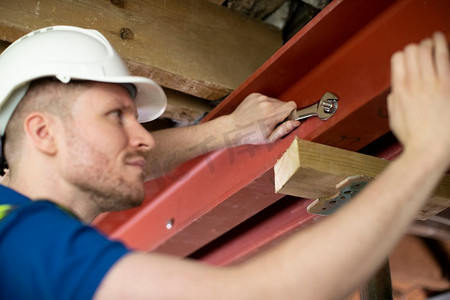 建筑工人在改造后的房屋天花板上安装钢支撑梁