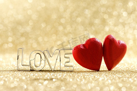两颗红色手工制作的木心和文字爱情在金色明亮的闪光灯下闪耀着波克背景。木质的心和文字的爱
