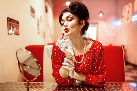 性感的别针女人与明亮的口红在手坐在镜子，衣服与波尔卡点，复古风格。复古咖啡馆50美式时尚