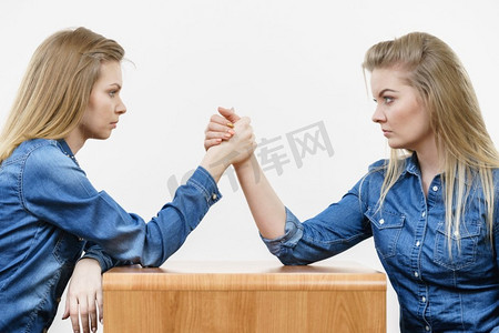 两个严重的竞争妇女有掰手腕打架，互相竞争。两个女人有手臂摔跤战斗
