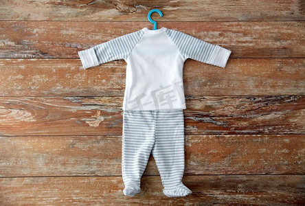 婴儿时代和衣服概念—婴儿衣服套衬衫和连衣裤有衣架在木桌上。木桌上挂有衣架的婴儿衣服