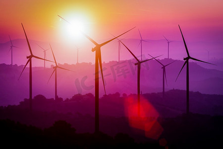 日落时分，风力涡轮机在山上的剪影。可再生清洁能源概念及风能可持续发展业务。