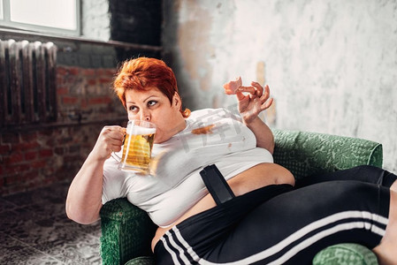 超重的女人喝啤酒吃三明治，暴食症，肥胖。不健康的生活方式，肥胖女性