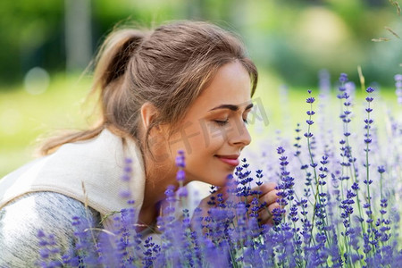花好月正圆摄影照片_园艺和人的概念—快乐的年轻妇女闻熏衣草花在夏季花园。年轻女子闻熏衣草花在花园