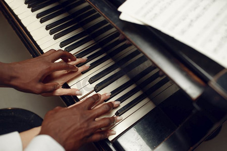 乌木大钢琴演奏者手放在键上，古典音乐。黑人表演者摆在乐器上