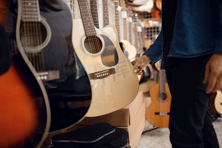 音乐培训psd摄影照片_男顾客在音乐商店选择原声吉他。乐器店的组合，音乐家购买设备