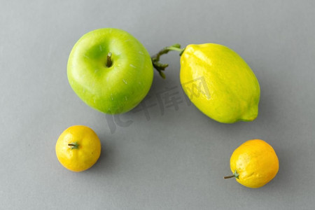 食物、水果和健康饮食概念—近摄青苹果和柠檬在灰色。关闭绿色苹果和柠檬在灰色