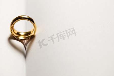 金典简约科幻图案摄影照片_两枚金色的结婚戒指放在空白的书页上，背景上有文字的复制空间。书上有金结婚戒指