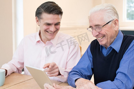 男邻居向老年男子展示如何使用数字平板电脑