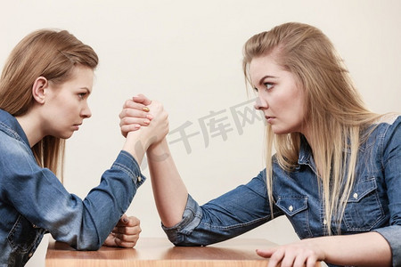 两个严重的竞争妇女有掰手腕打架，互相竞争。两个女人有手臂摔跤战斗