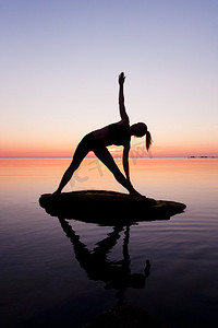 高加索健身妇女练习瑜伽在海滩在日落。高加索健身妇女练习瑜伽