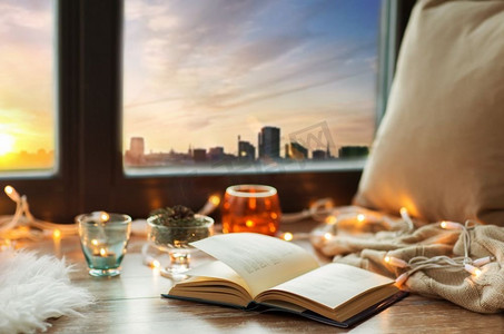 温馨舒适的家居概念书，窗台上的花环灯和蜡烛。书本、花环和窗台上的蜡烛