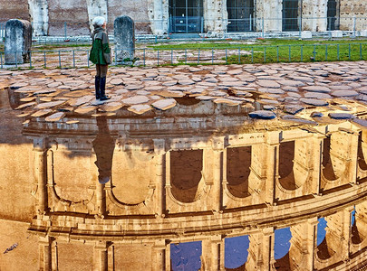 妇女游客在鹅卵石砖铺湿街道与斗兽场反射在罗马，意大利
