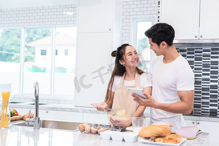 情人节主题摄影照片_亚洲夫妇烹饪和烘焙蛋糕一起在厨房在家里。爱和幸福概念甜蜜的蜜月和情人节主题