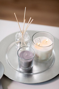 装饰，卫生和芳香疗法的概念-芳香芦苇扩散器，蜡烛燃烧在托盘上。香草扩散器托盘上燃烧的蜡烛