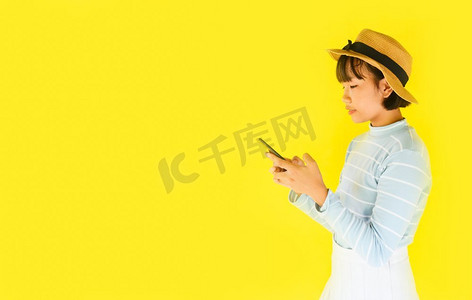 小女孩手持智能手机黄底/亚洲年轻女子用手机夏日时髦