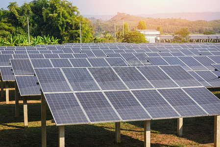 太阳能电池板的视图在太阳能农场与绿树和阳光照明反射/太阳能电池能量或可再生能源概念