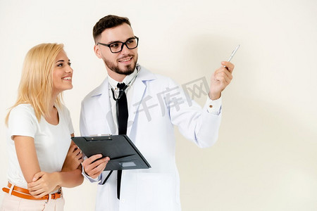 复印摄影照片_男医生站在女病人旁边的时候把笔指向空的复印空间。男医生与病人点笔在复印空间。