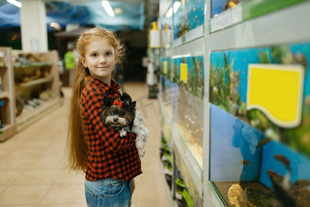 小女孩带着小狗在水族馆、宠物店看鱼。孩子们在宠物店买设备。在水族馆、宠物店看鱼的女孩