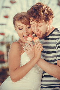 暑假与快乐概念吃冰淇淋的年轻夫妇户外在游乐园摩天轮在背景