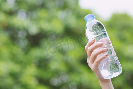 在公园里，一名年轻男子手持塑料瓶子里的新鲜饮水瓶。