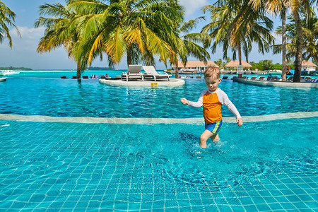 三岁的蹒跚学步的男孩在度假村游泳池。暑假在马尔代夫度假。