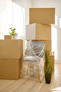 堆在室内的纸箱和椅子。搬家的日子。家庭或办公室搬迁。室内堆叠的纸板箱和包装椅子