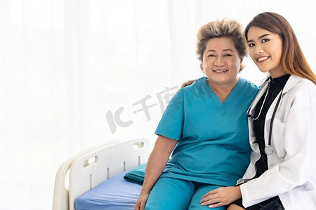 身着制服的年轻女医生在医院病房探视老年妇女患者时拥抱并微笑着