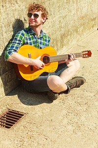 音乐与人的概念年轻的胡子潮人与吉他户外在街上