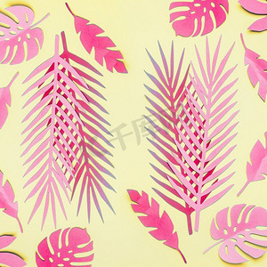 粉红色的热带树叶平放在黄色的背景上。有创意的布局。各种热带树叶组成