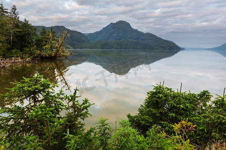 宁静的景色由山湖在加拿大与岩石在平静的水中的反射。