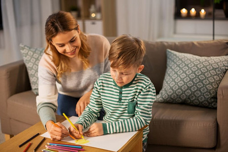 家庭，休闲和人的概念—母亲和小儿子与彩色铅笔和纸提请在家里。母亲和儿子与铅笔绘画在家里