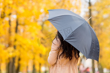 赛季摄影照片_季节，下雨的天气和人的概念—有伞的年轻妇女在秋天公园。有伞的年轻女子在秋天公园