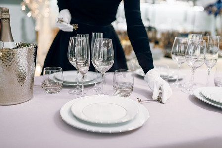 女服务员戴着手套把刀，摆在桌子上。服务，节日晚宴装饰。女服务员戴手套把刀，桌子设置
