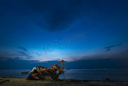 日落时，一艘渔船在海滩上沉没