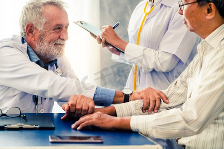 资深男医生在医院办公室与老年病人交谈。医疗保健和医生员工服务理念。