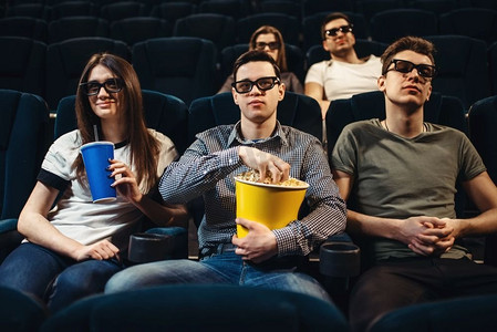 人们在3d眼镜与爆米花和饮料看电影在电影院。娱乐业。人与爆米花看电影在电影院